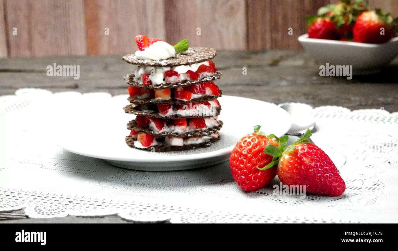 Wüste der Erdbeeren mit Sahne und Waffel serviert auf Platte über der Tischplatte. Stockfoto