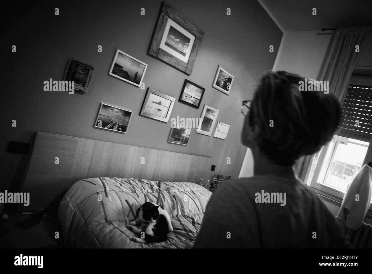 Italien, Cuggiono, Betty, bevor sie für eine andere Operation ins Krankenhaus gebracht wird, schaut sich ihre Fotografien an, die an der Wand im Schlafzimmer hängen. Stockfoto