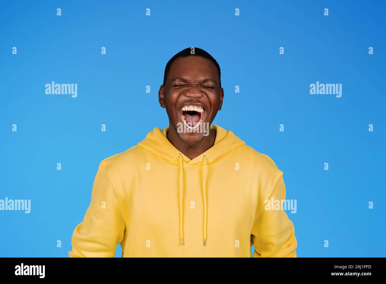 Fröhlich lachend begeistert, tausendjähriger afroamerikaner im Sweatshirt mit weit geöffnetem Mund, genießen Sie Gewinn Stockfoto Fröhlich lachend begeistert, tausendjähriger afroamerikaner im Sweatshirt mit weit geöffnetem Mund, genießen Sie Gewinn Stockfoto