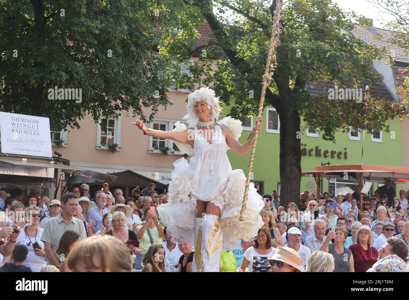 20. August 2023, Thüringen, Bad Sulza: Eine Salzfee auf Stelzen spaziert beim 29. Thüringer Weinfest über den Marktplatz. Foto: Bodo Schackow/dpa Stockfoto