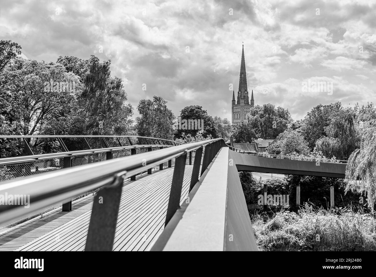 Lange Geländer und Holzplanken auf der Jarrold Bridge führen in Richtung Norwich Cathedral, die im August 2023 über dem Wensum abgebildet wurde. Stockfoto