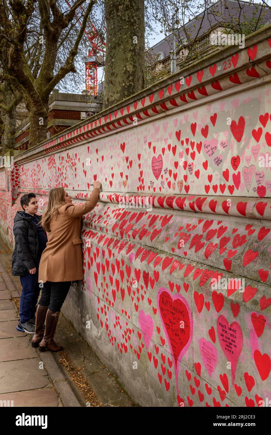 Eine Dame schreibt über „die nationale COVID-Gedenkmauer“, ein öffentliches Wandgemälde zum Gedenken an die Opfer der COVID-19-Pandemie im Vereinigten Königreich. Dehnen Stockfoto