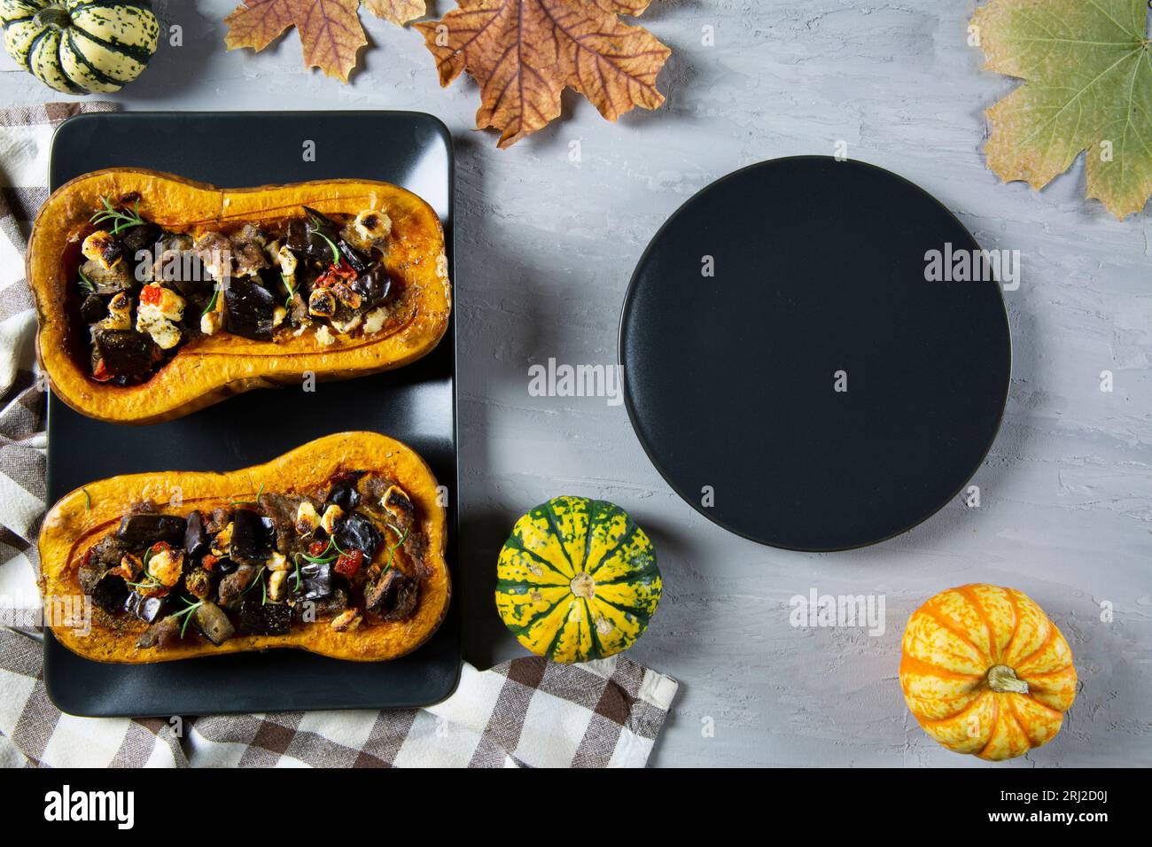 Gefüllter Kürbis auf schwarzen Tellern, Draufsicht. Thanksgiving traditionelle saisonale Speisen. Stockfoto