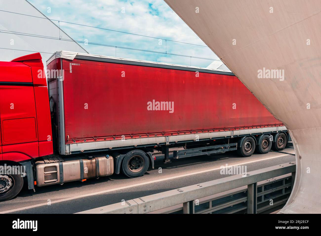 Roter Sattelzug mit Anhänger über eine Brücke. Industrielles Transportkonzept. Selektiver Fokus. Stockfoto