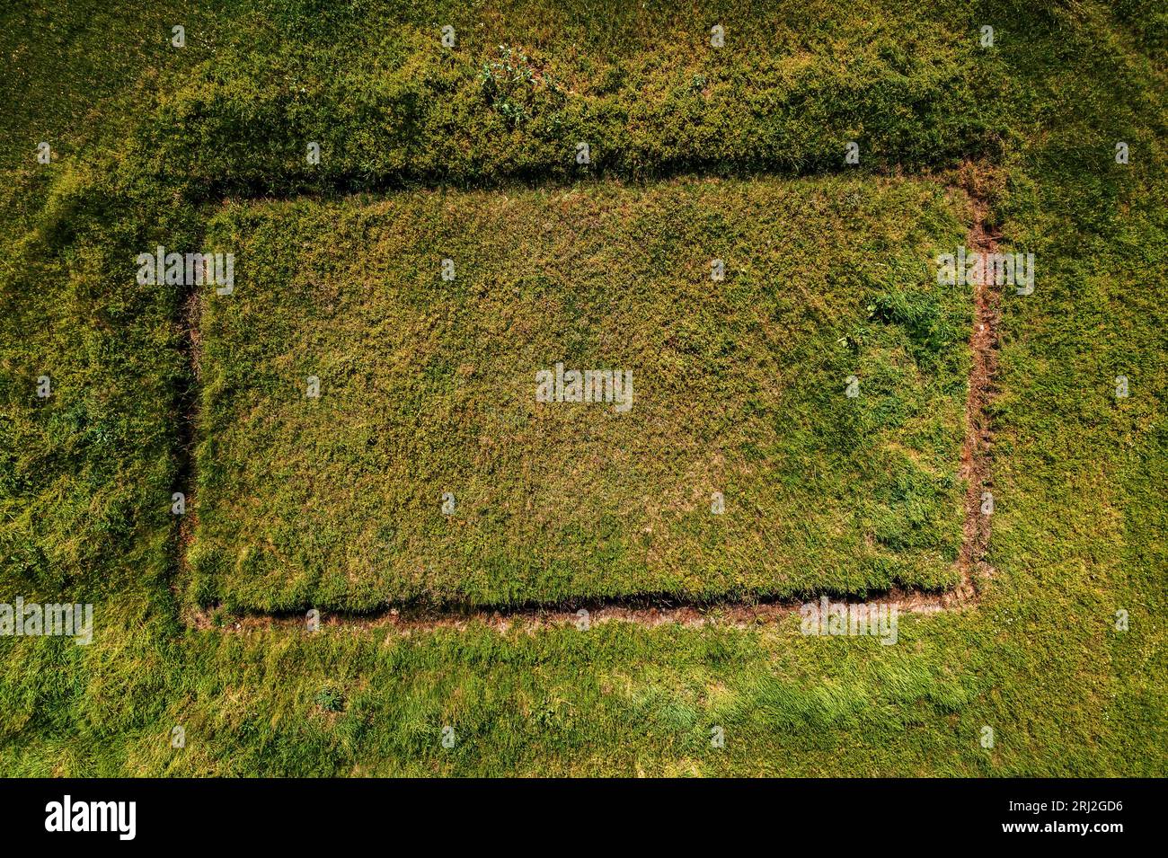 Luftaufnahme eines unvollendeten Hausfundamentes auf dem Grasfeld von der Drohne pov, rechteckige Form auf der Wiese als Hintergrundbild für soziale Medien, Draufsicht Stockfoto
