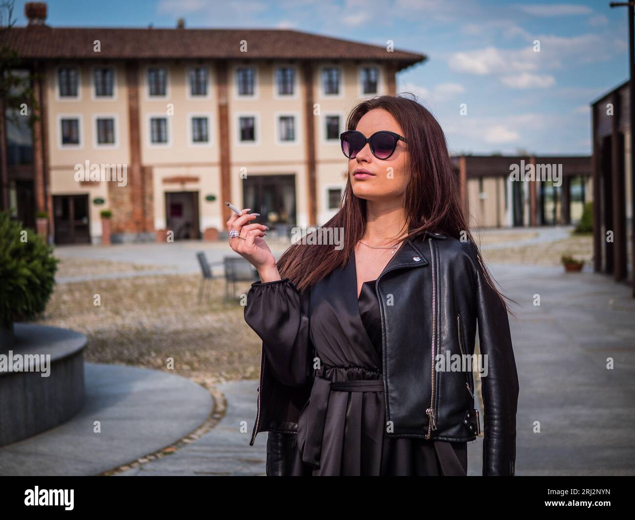 Foto einer Frau in einer schwarzen Lederjacke, die eine Zigarette raucht Stockfoto