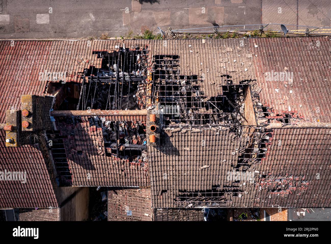 Luftaufnahme direkt über einer Reihe verbrannter und verfallener Reihenhäuser im Norden Englands mit Dachschäden nach einem Hausbrand Stockfoto