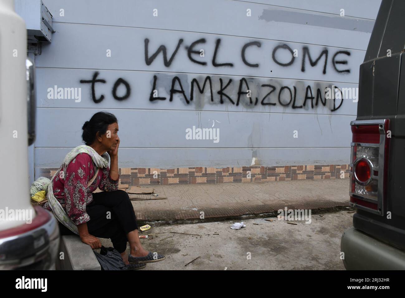 Churachandpur, Indien. August 2023. Eine Kuki-Frau telefoniert vor einem Graffiti im Bezirk Churachandpur im Nordosten von Manipur. Auf dem Weg von der Bezirksgrenze von Bishnupur zum Bezirk Churachandpur in Manipur, wo die andauernde Gewalt begann, wurden fast alle Schilder vor Häusern, Geschäften, Regierungsinstitutionen und Büros, die den Namen „Churachandpur“ trugen, mit dem Namen „Lamka“ besprüht (Foto: Biplov Bhuyan/SOPA Images/SIPA USA) Kredit: SIPA USA/Alamy Live News Stockfoto