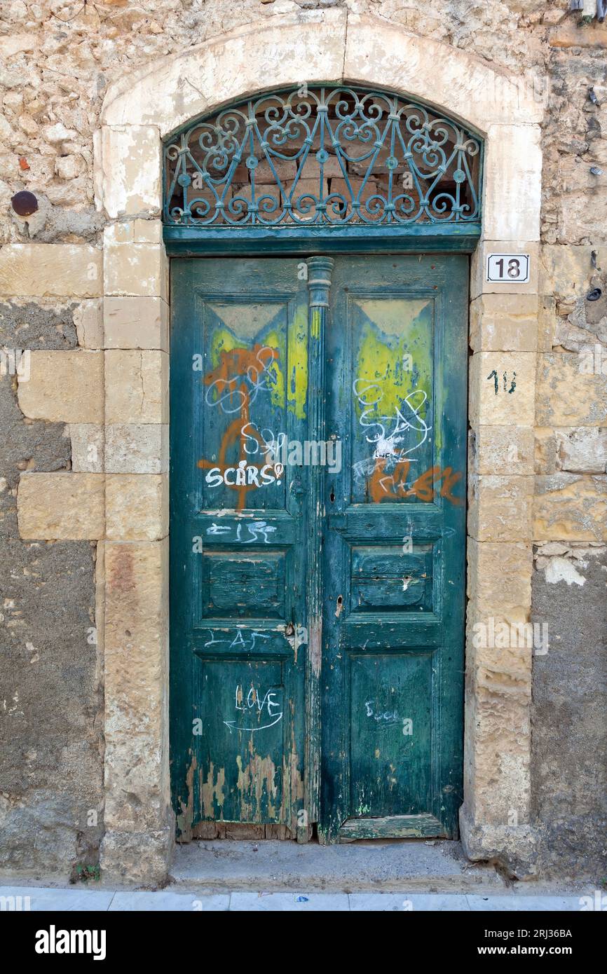 Alte verwitterte Holztür mit erstaunlichem Steinbogen-Sturz in einem verlassenen alten Herrenhaus in der Altstadt von Rethymno, auf Kreta, Griechenland, Europa. Stockfoto