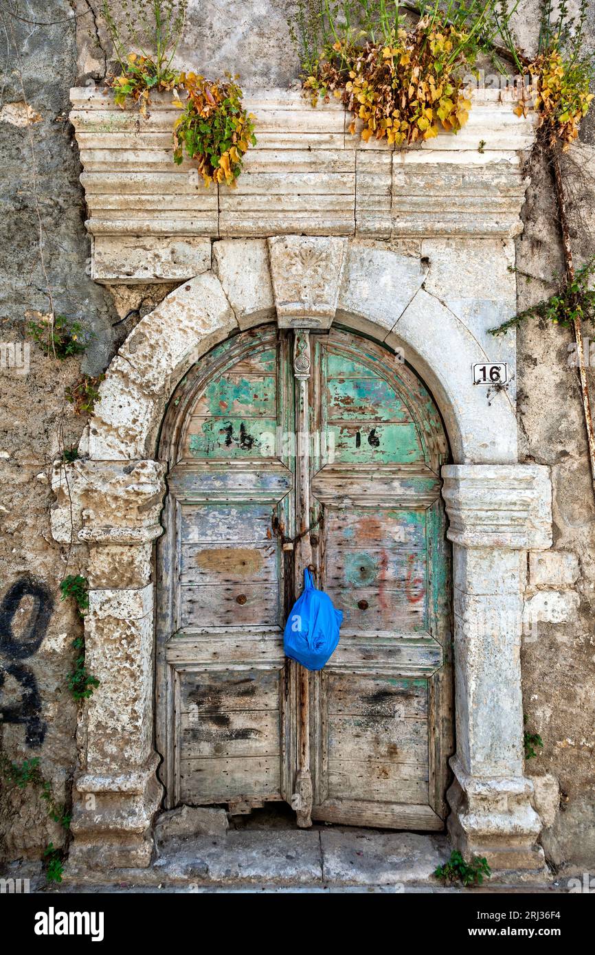 Alte verwitterte Holztür mit erstaunlichem Steinbogen-Sturz in einem verlassenen alten Herrenhaus in der Altstadt von Rethymno, auf Kreta, Griechenland, Europa. Stockfoto