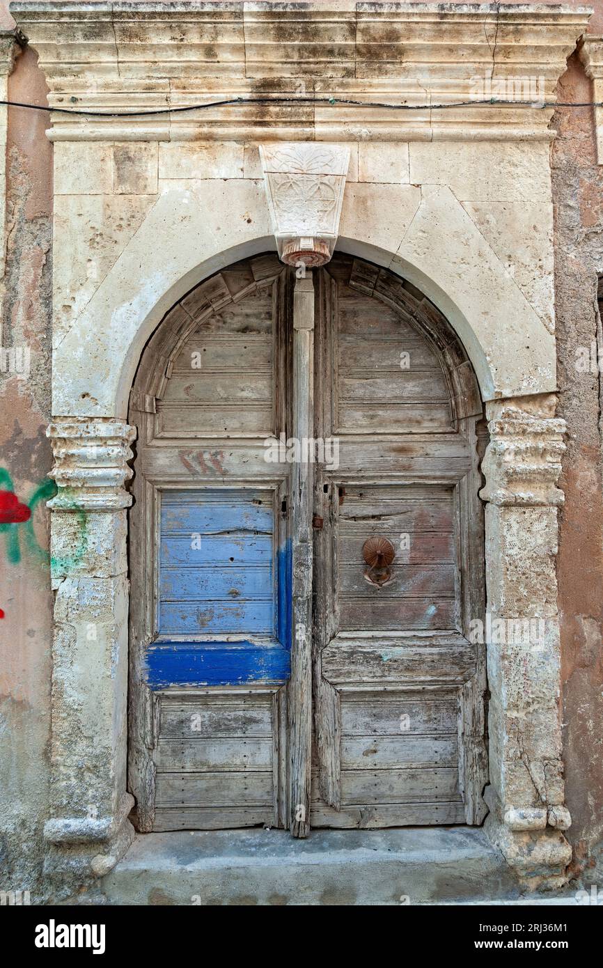 Alte Wetter Holztür mit Steinbogen Sturz in einem verlassenen alten Herrenhaus in der Altstadt von Rethymno, auf der Insel Kreta, Griechenland, Europa. Stockfoto