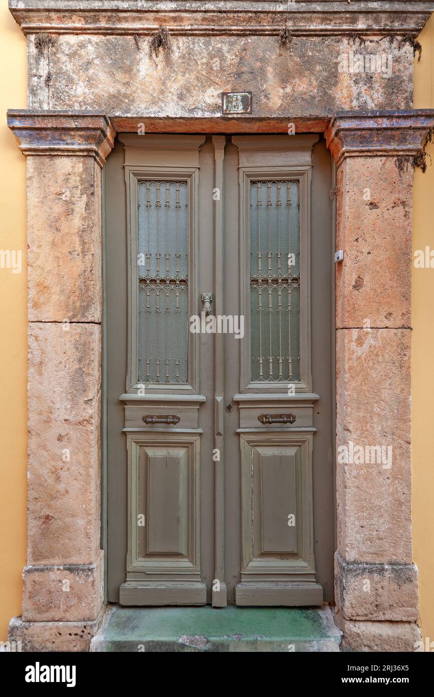 Wunderschöne Tür mit Glasfenstern in einem alten, traditionellen Herrenhaus mit Steinsturz, in der Altstadt von Ägina, auf der Insel Ägina, Griechenland, Europa. Stockfoto