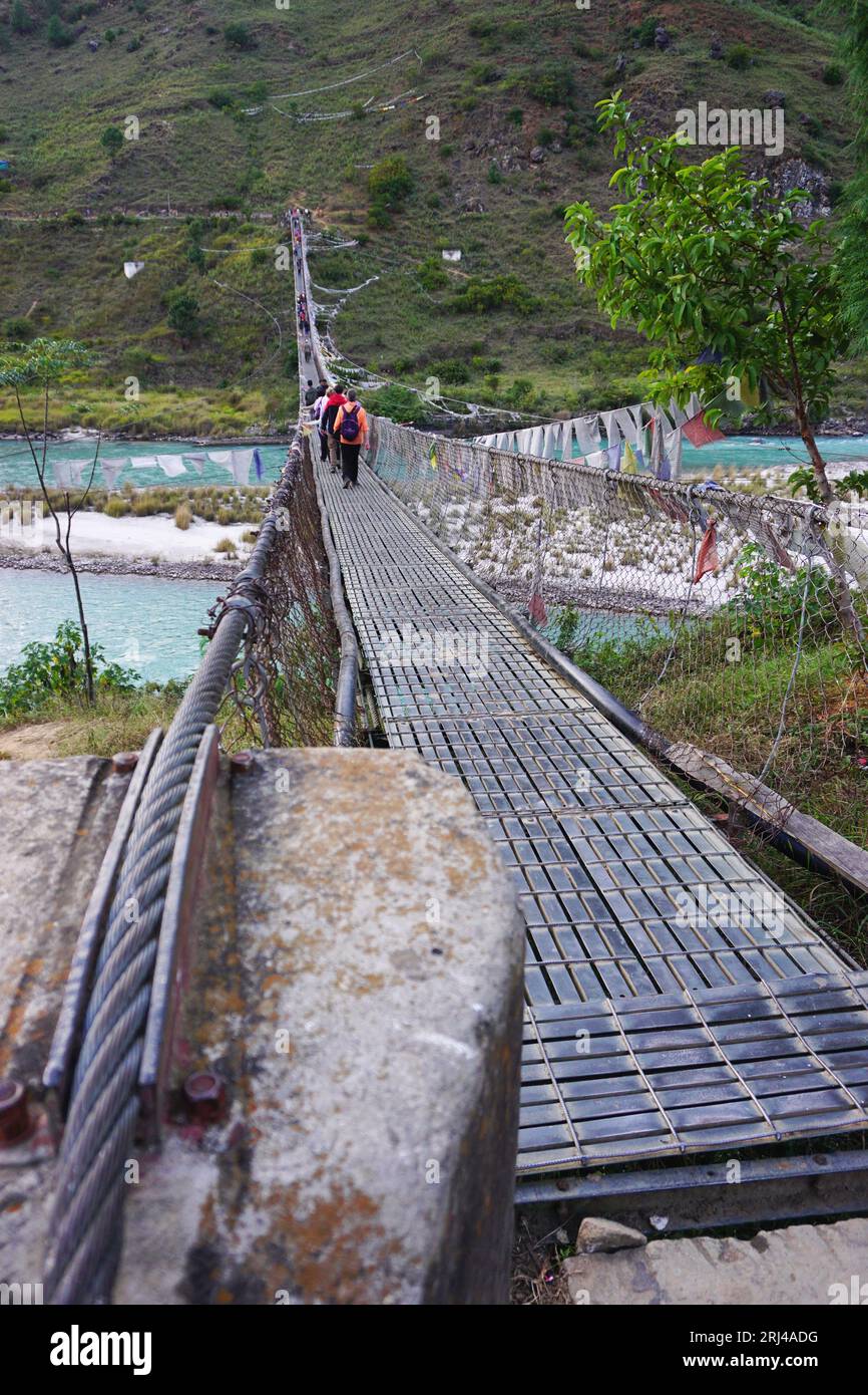 Langer Blick auf die Hängebrücke von Punakha mit Ankerkabel im Vordergrund und Menschen, die auf dem Stahldeck über den Fluss Pho Chhu, Bhutan, gehen Stockfoto