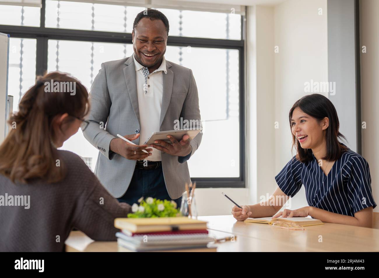 Eine multirassische Gruppe junger Schüler, die Englisch mit einem afroamerikanischen Lehrer lernen, Ideen austauschen und den Unterricht genießen. Bildungskonzept Stockfoto