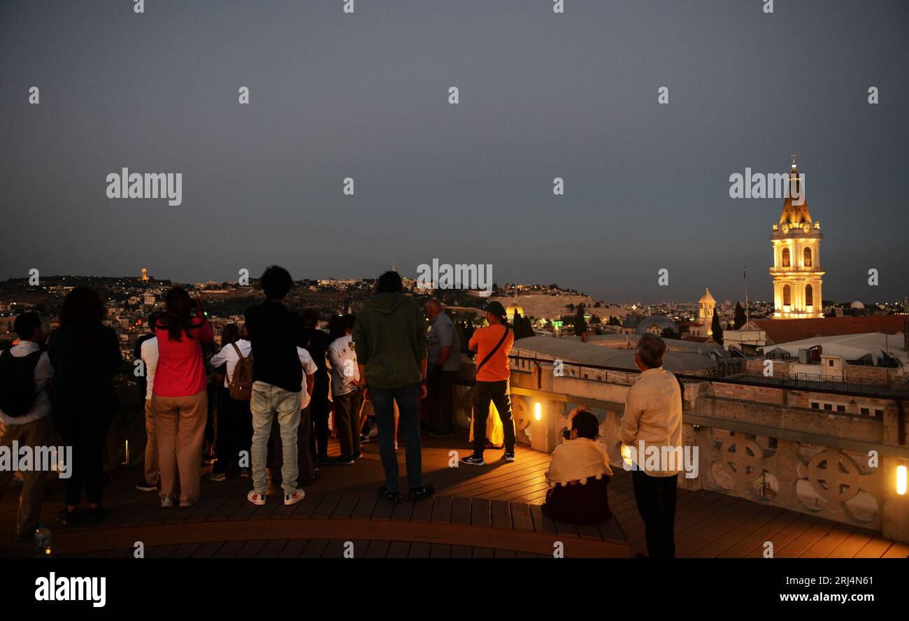 Touristen genießen den Blick auf die Altstadt mit dem beleuchteten Uhrturm des Klosters des Heiligen Erlösers. Jerusalem, Israel. Stockfoto