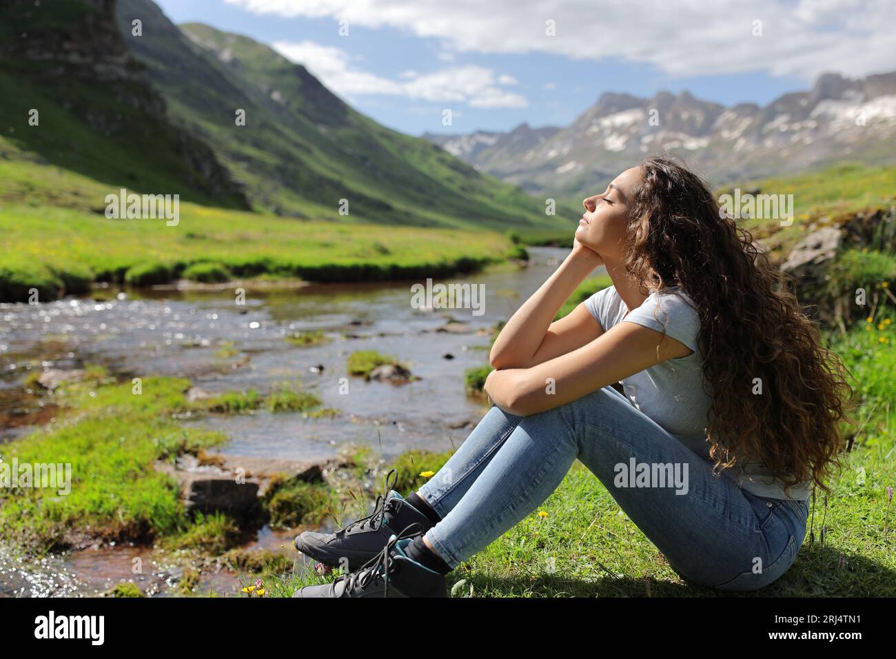 Profil einer Frau, die sich mit geschlossenen Augen in einem Flussbett im Berg entspannt und ausruht Stockfoto