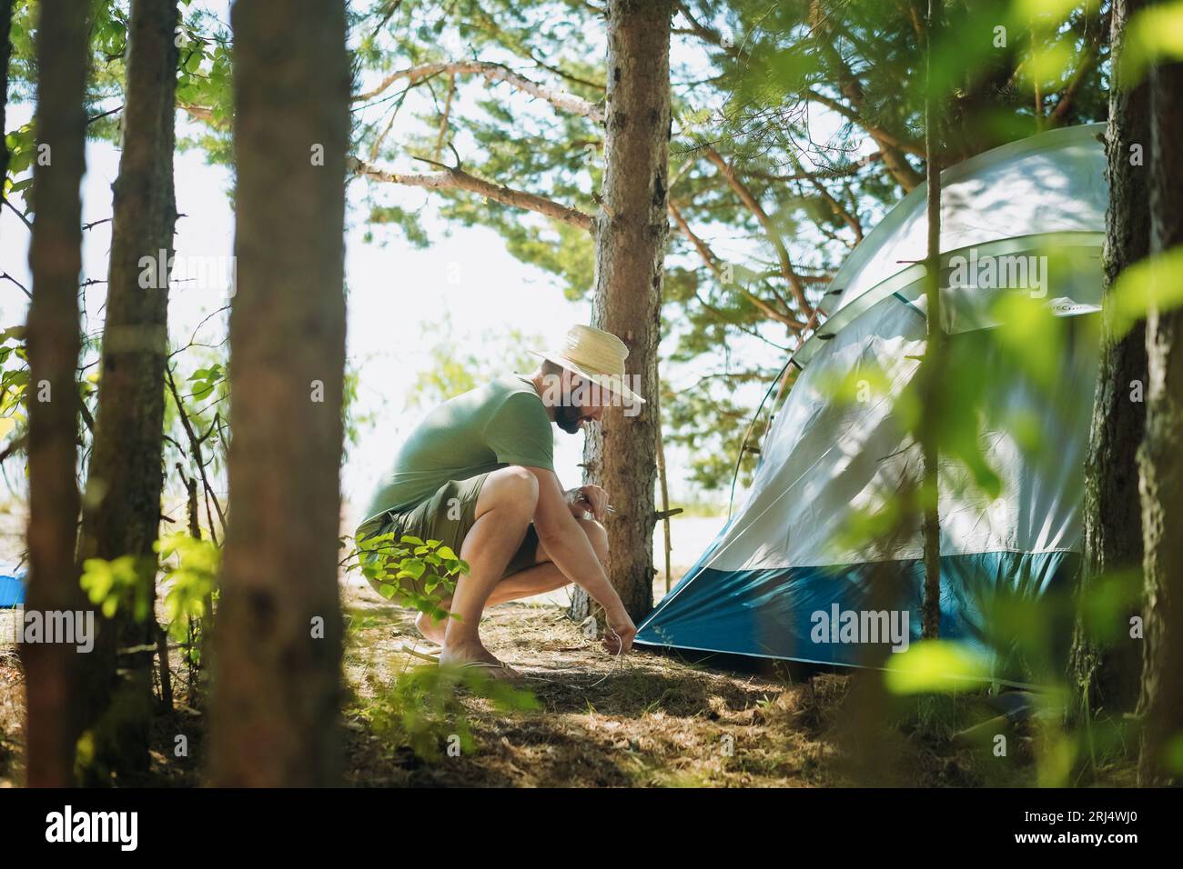 Ein weißer Mann mit Hut, der ein Zelt aufstellt. Familien-Campingkonzept Familien-Campingkonzept. Hochwertiges Foto Stockfoto