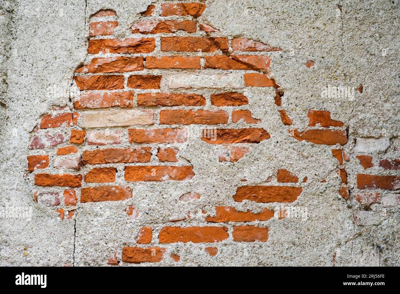 Rote Ziegelwand mit gefallenem Putz. Rustikaler Hintergrund. Grundige Tapeten. Stockfoto
