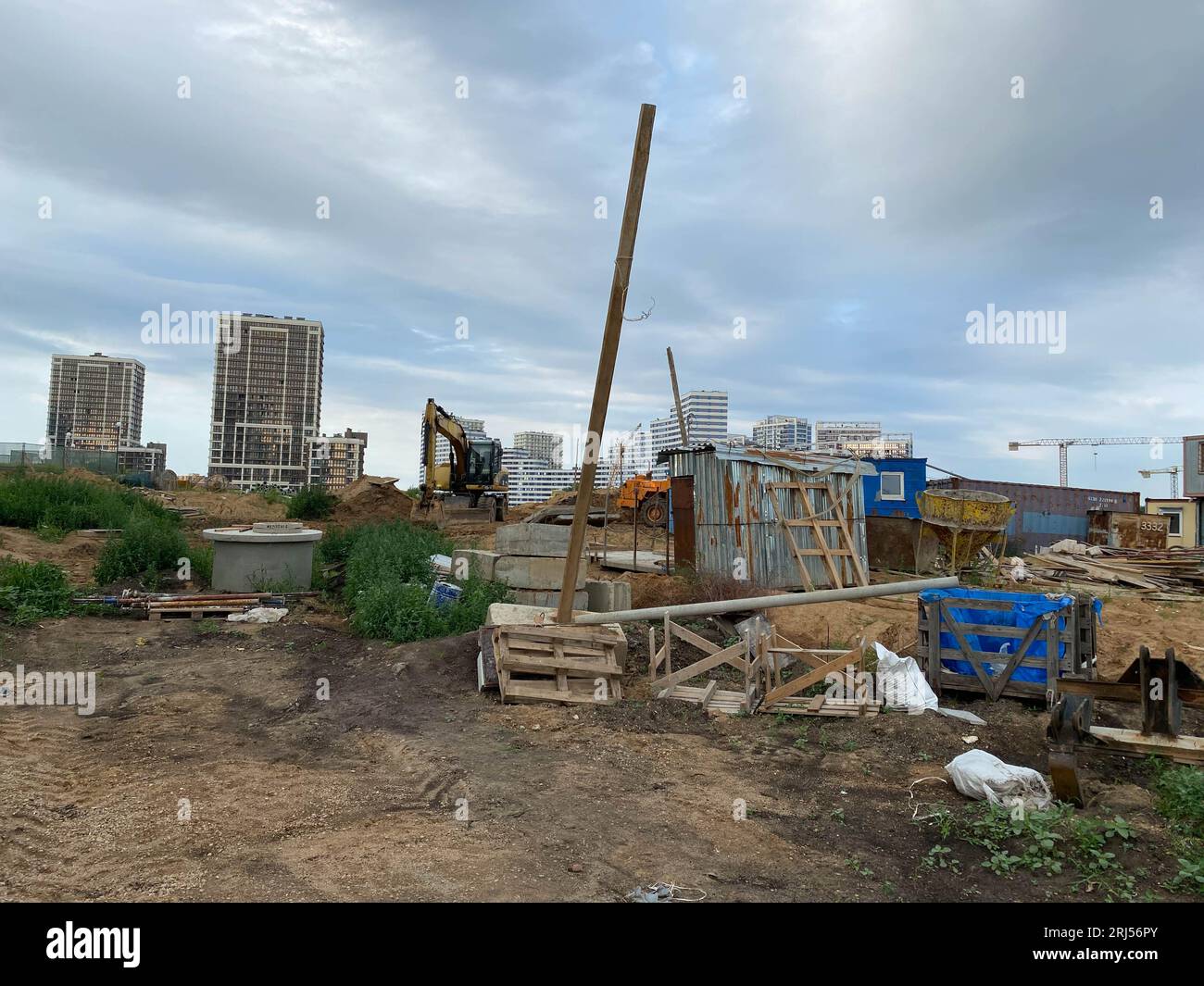 Arbeiten am Platz mit vielen hohen Gebäuden im Bau und Kranichen unter blauem Himmel. Stockfoto