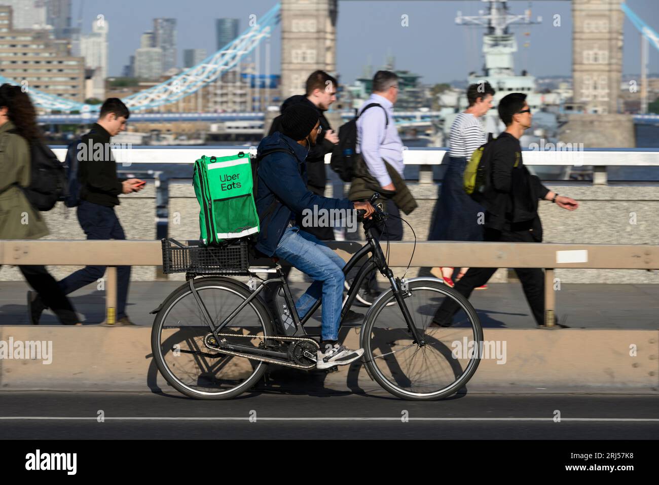 Ein Uber isst Fahrradkurier, der ein E-Bike über die London Bridge, London, Großbritannien, fährt. 7. Juni 2023 Stockfoto