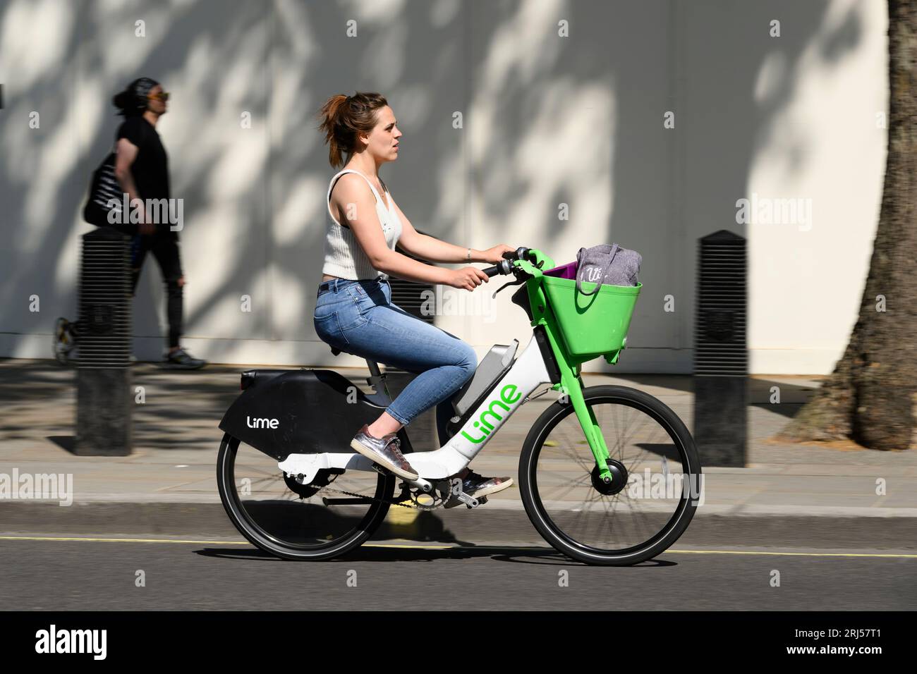 Eine Frau, die mit einem Lime-Elektrofahrrad in Whitehall, London, Großbritannien, fährt. 7. Juni 2023 Stockfoto