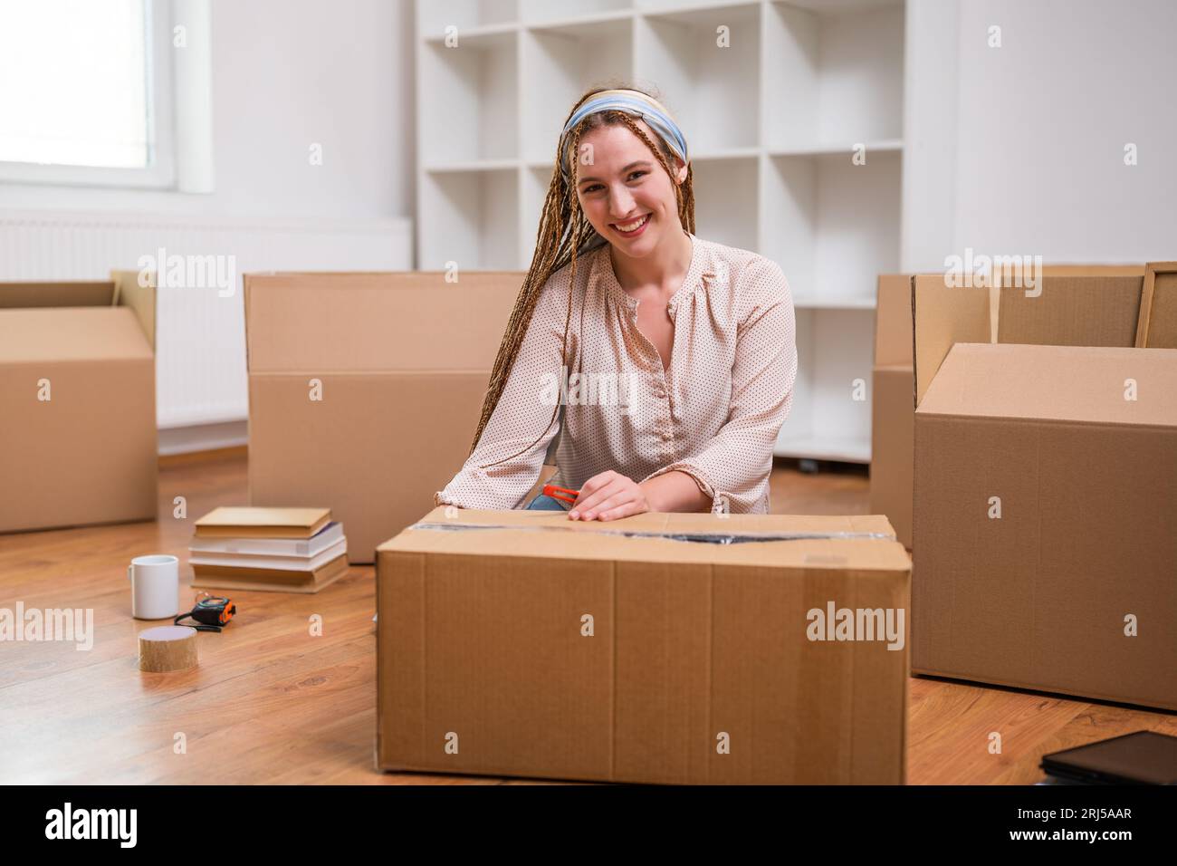 Moderne Ingwerfrau mit Zöpfen zieht in ein neues Zuhause. Stockfoto