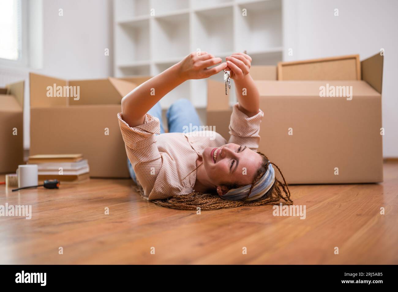 Glückliche Ingwerfrau mit Zöpfen, die den Schlüssel zu ihrem neuen Zuhause halten. Stockfoto