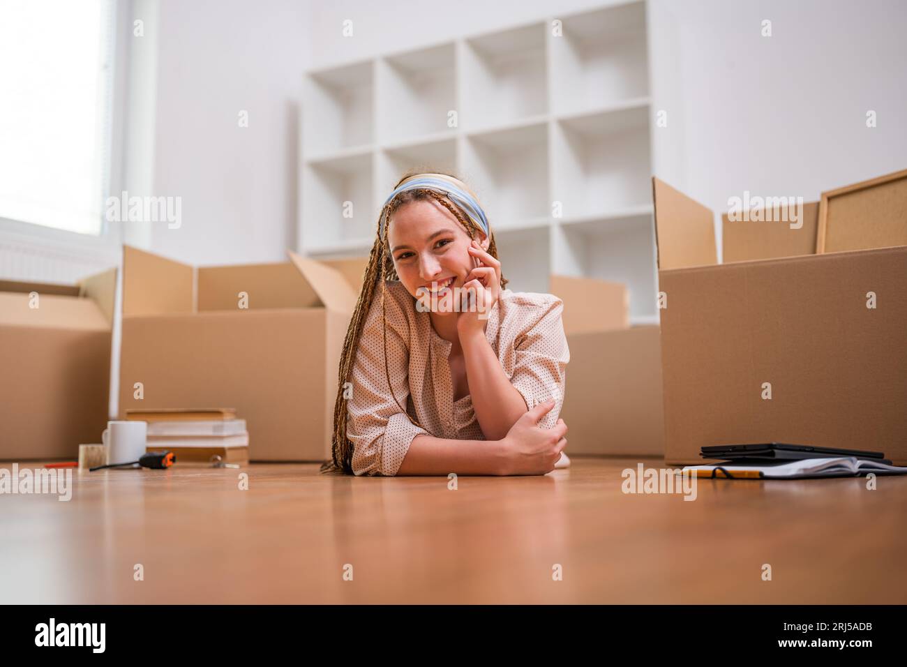 Moderne Ingwerfrau mit Zöpfen zieht in neue Wohnung. Stockfoto