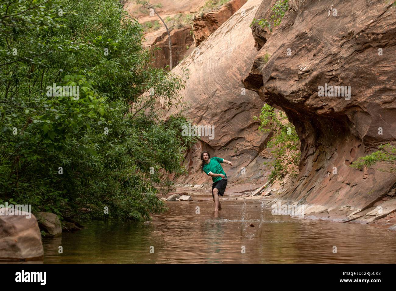 Junger Mann springt Steine in den Bach Stockfoto