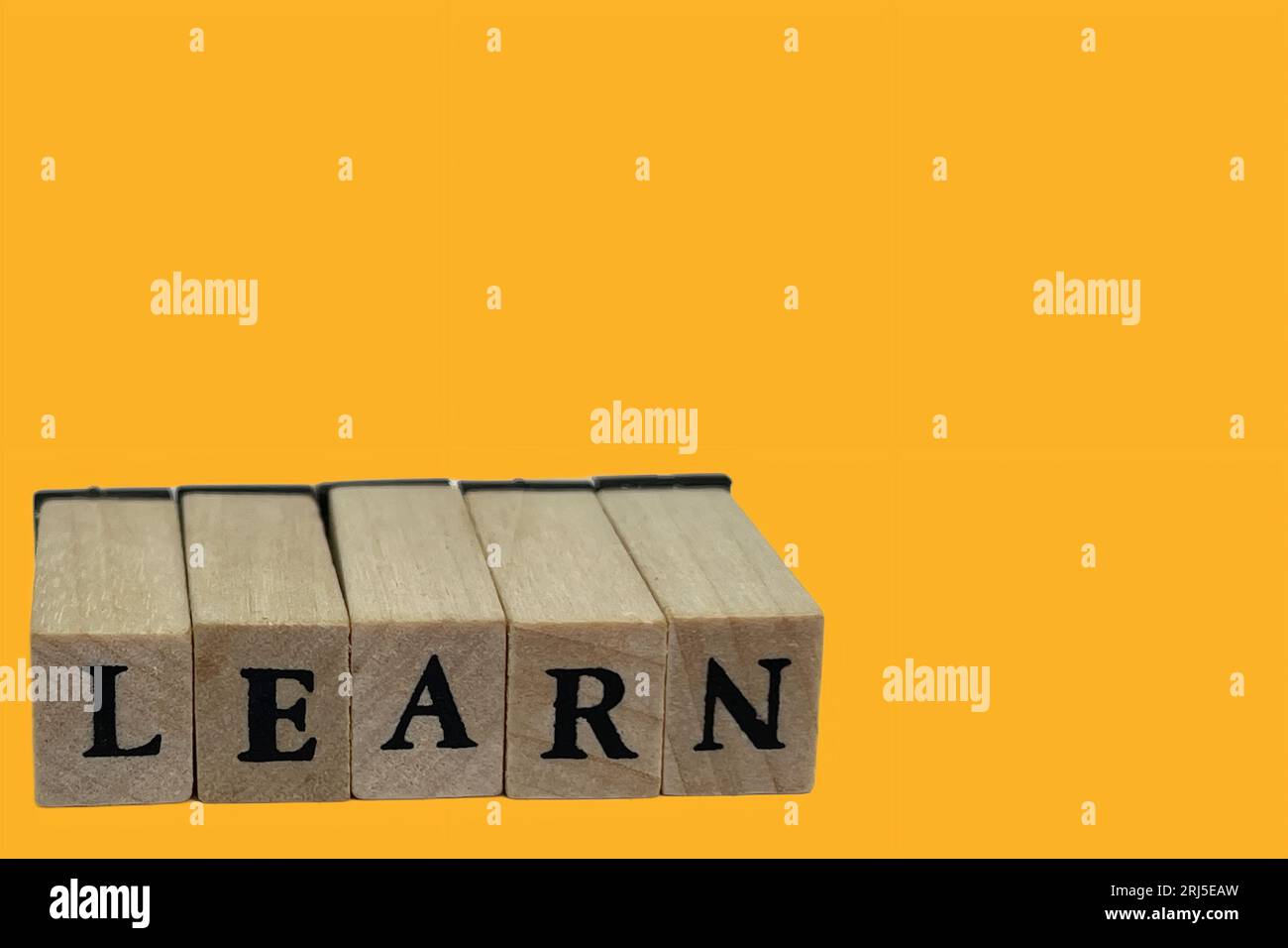 Ein heller gelber Hintergrund mit hölzernen Buchstabenblöcken, die das Wort „Lernen“ buchstabieren Stockfoto