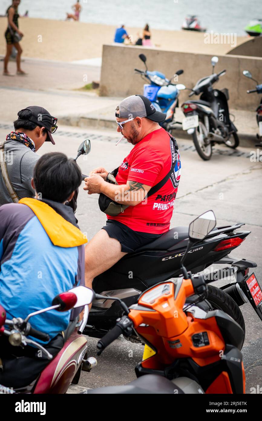Ein Mann bekommt seinen Führerschein überprüft, während er sein Motorrad entlang der Beach Rd. Fährt Pattaya, Thailand. Stockfoto