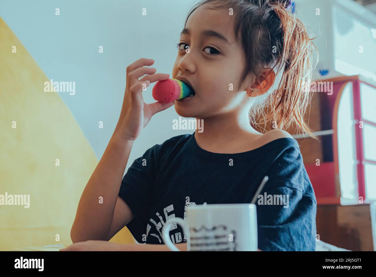 Eine Nahaufnahme eines asiatischen Mädchens, das einen Snack isst Stockfoto