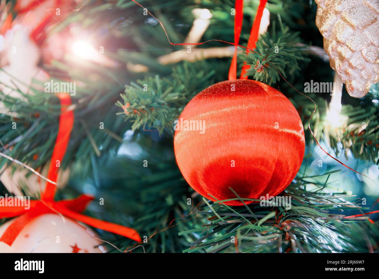 Neujahrsdekorierte Baumzweige mit knallroter Kugel und Kranzband. Traditionelle festliche Hintergrundbilder Stockfoto
