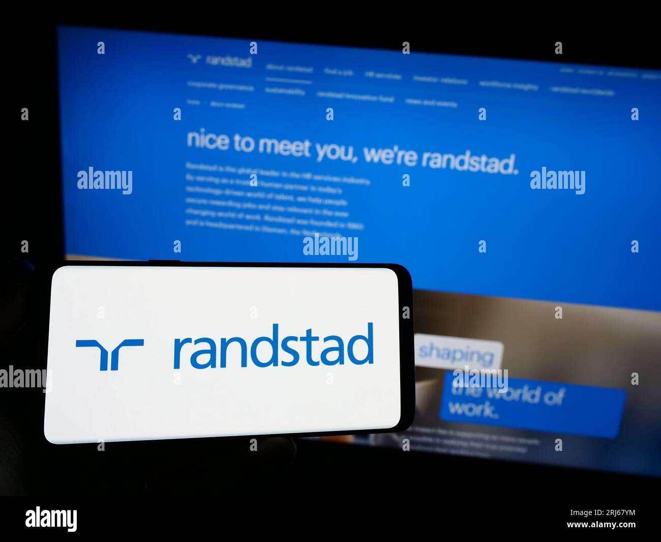 Person, die ein Smartphone mit dem Logo des niederländischen Personalunternehmens Randstad N.V. auf dem Bildschirm vor der Website hält. Konzentrieren Sie sich auf das Display des Telefons. Stockfoto