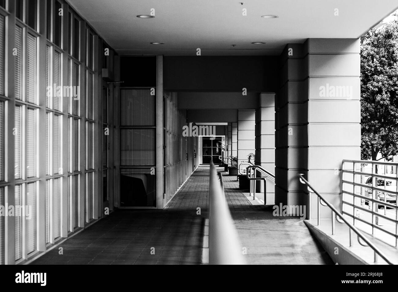 Ein Schwarzweißbild eines langen, schwach beleuchteten Korridors mit einem schmalen Durchgang Stockfoto