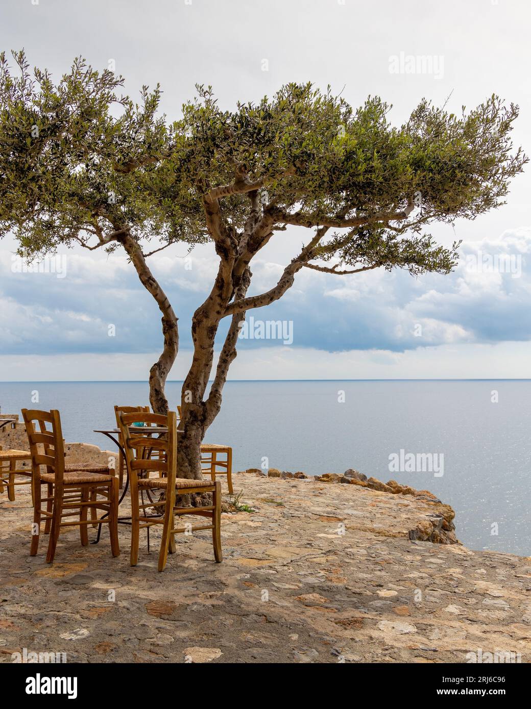 Ein Stühle im Freien am Rande eines ruhigen Sees, mit einem atemberaubenden Blick auf das Wasser in Monemvasia Castle Griechenland Stockfoto