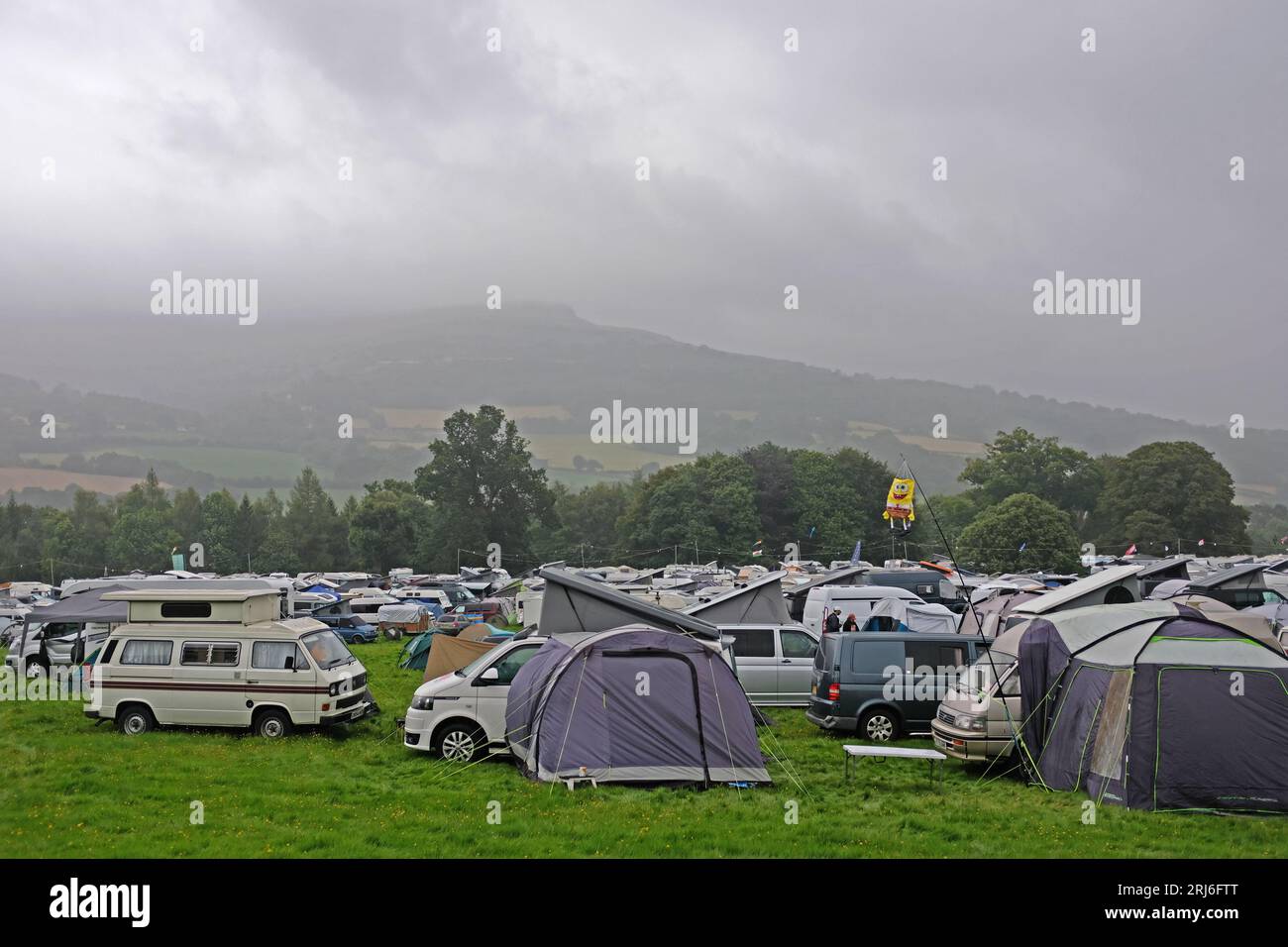 Vans und Zelte bei einem nassen und bewölkten Festival in Wales. Stockfoto