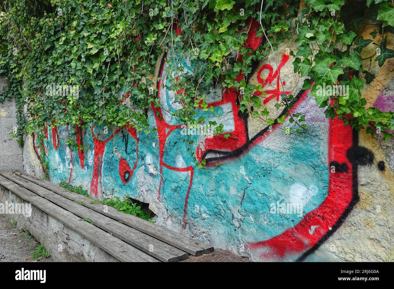 Eine lebendige städtische Szene mit Graffiti-Kunst auf einer großen Backsteinmauer im Vordergrund Stockfoto