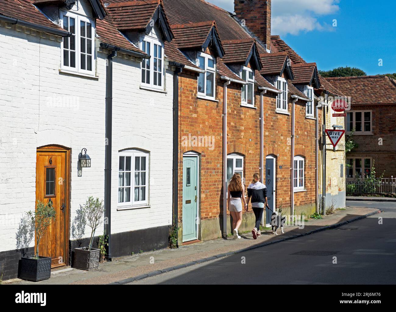 Zwei Mädchen, die an einer Reihe von Reihenhäusern im Dorf Brill, Buckinghamshire, England, vorbeigehen Stockfoto