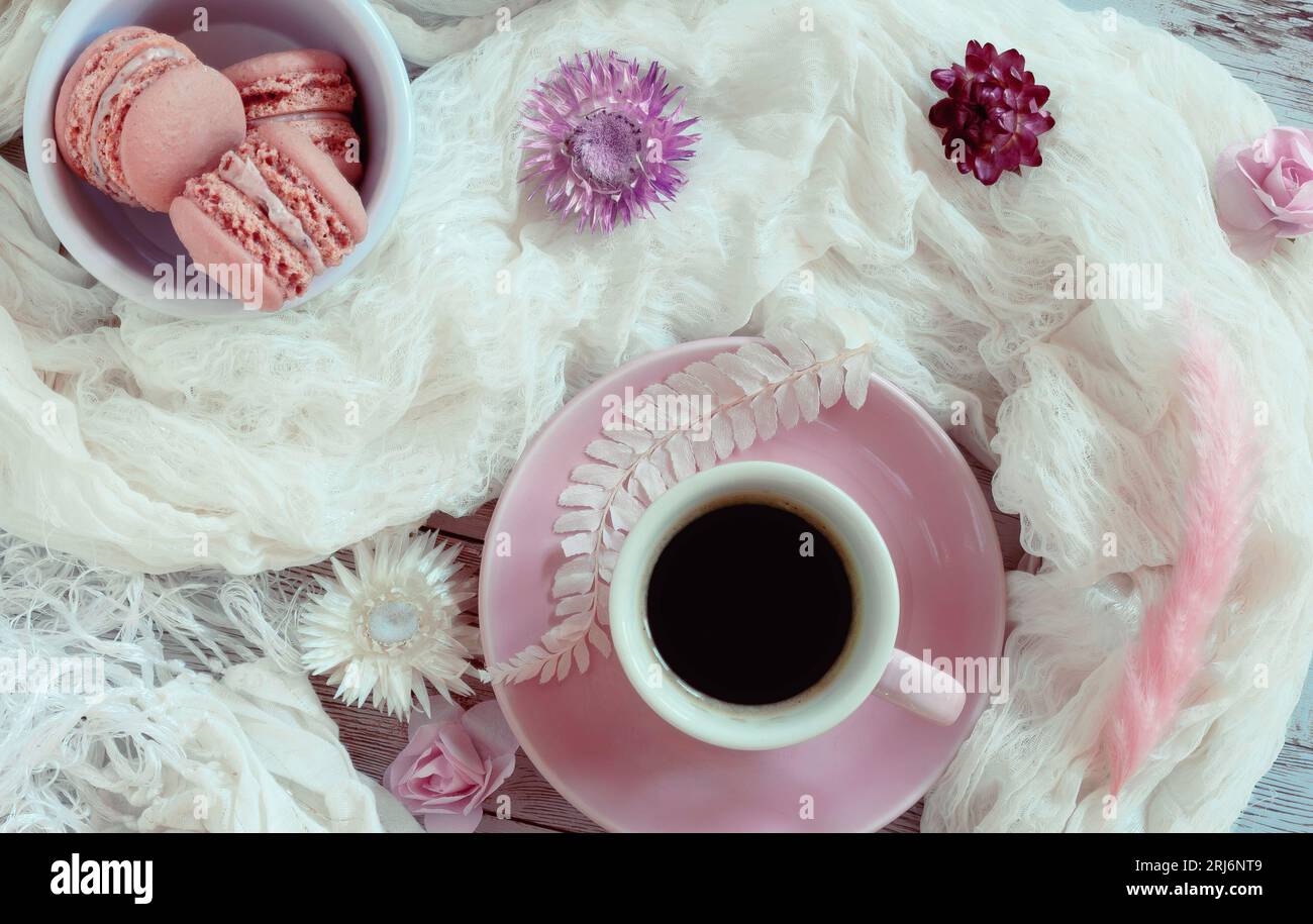 Pinkfarbene und weiße flache Schicht mit Kaffee, Makronen und getrockneten Blumen Stockfoto
