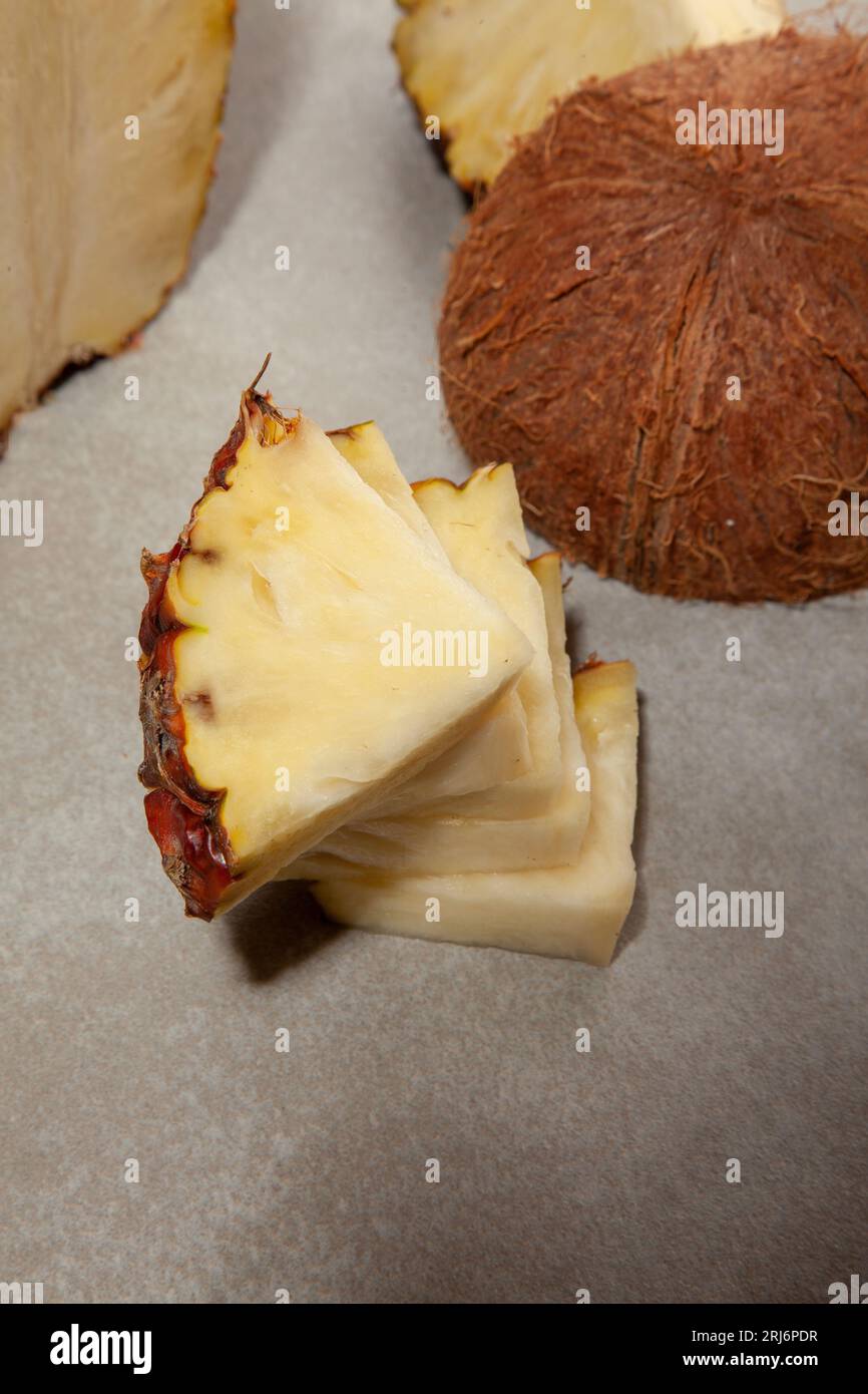 Ein vertikaler Schuss Ananasscheiben und Kokos auf einer Tischfläche Stockfoto