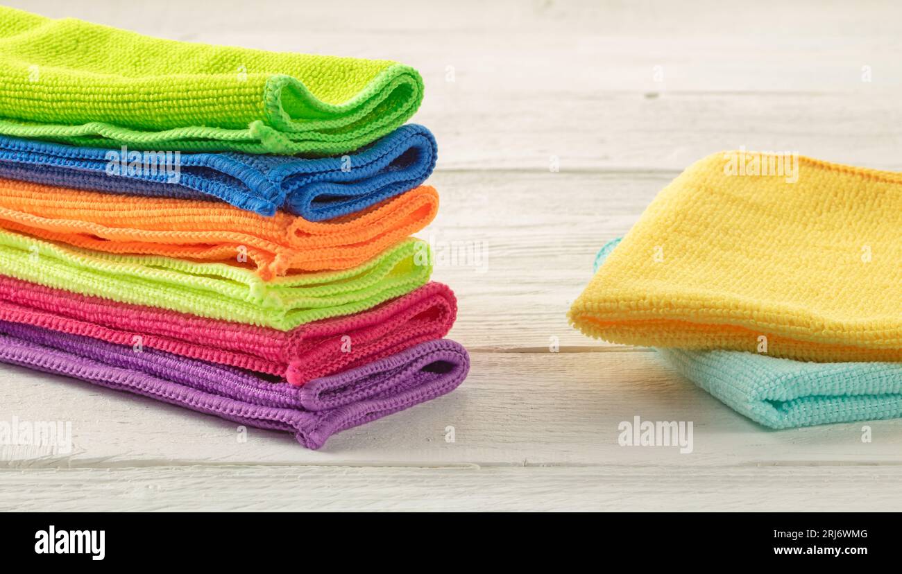 Stapel Küchenhandtücher aus Mikrofaser in hellen Farben auf weißem Holzgrund. Stockfoto