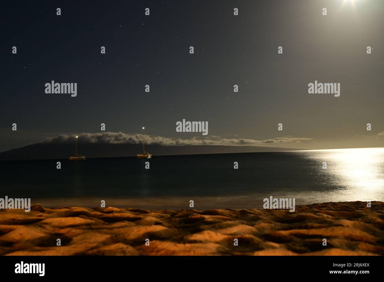 Ein ruhiger Strand, der bei Vollmond in einem klaren Nachthimmel erleuchtet wird Stockfoto