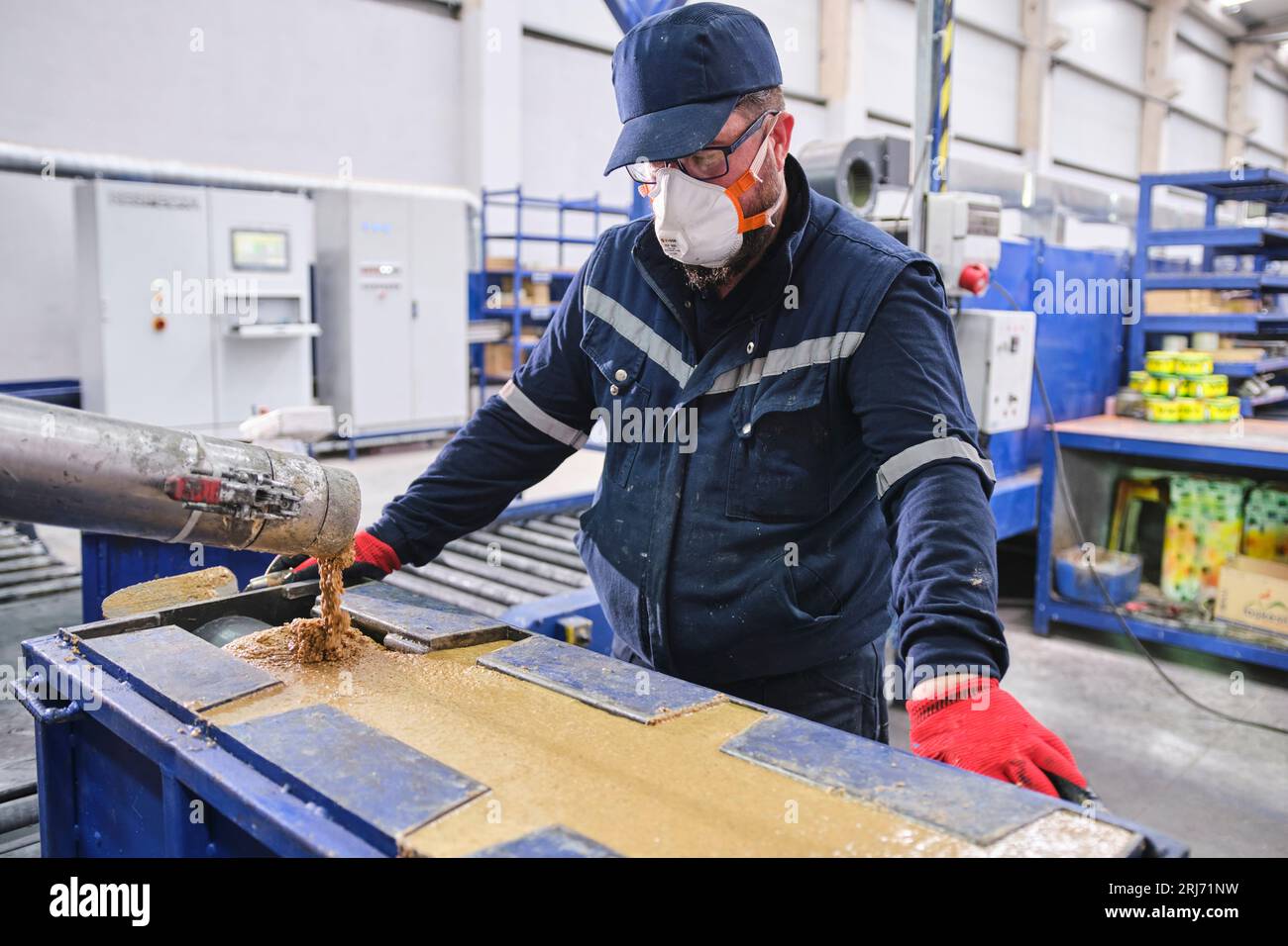 Werkarbeiter schüttet Zementmischung in eine Form und glättet sie mit einem Werkzeug. Stockfoto