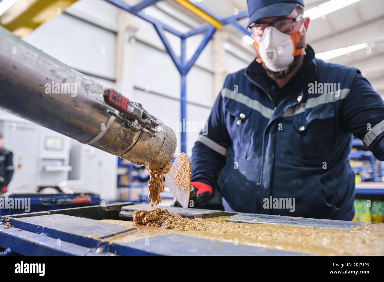 Werkarbeiter schüttet Zementmischung in eine Form und glättet sie mit einem Werkzeug. Stockfoto