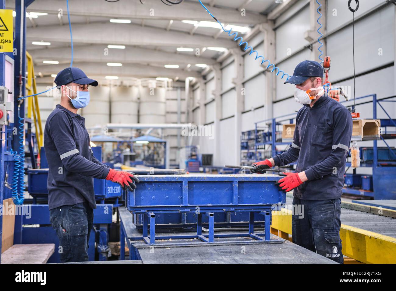 Werkarbeiter schüttet Zementmischung in eine Form und glättet sie mit einem Werkzeug. Stockfoto