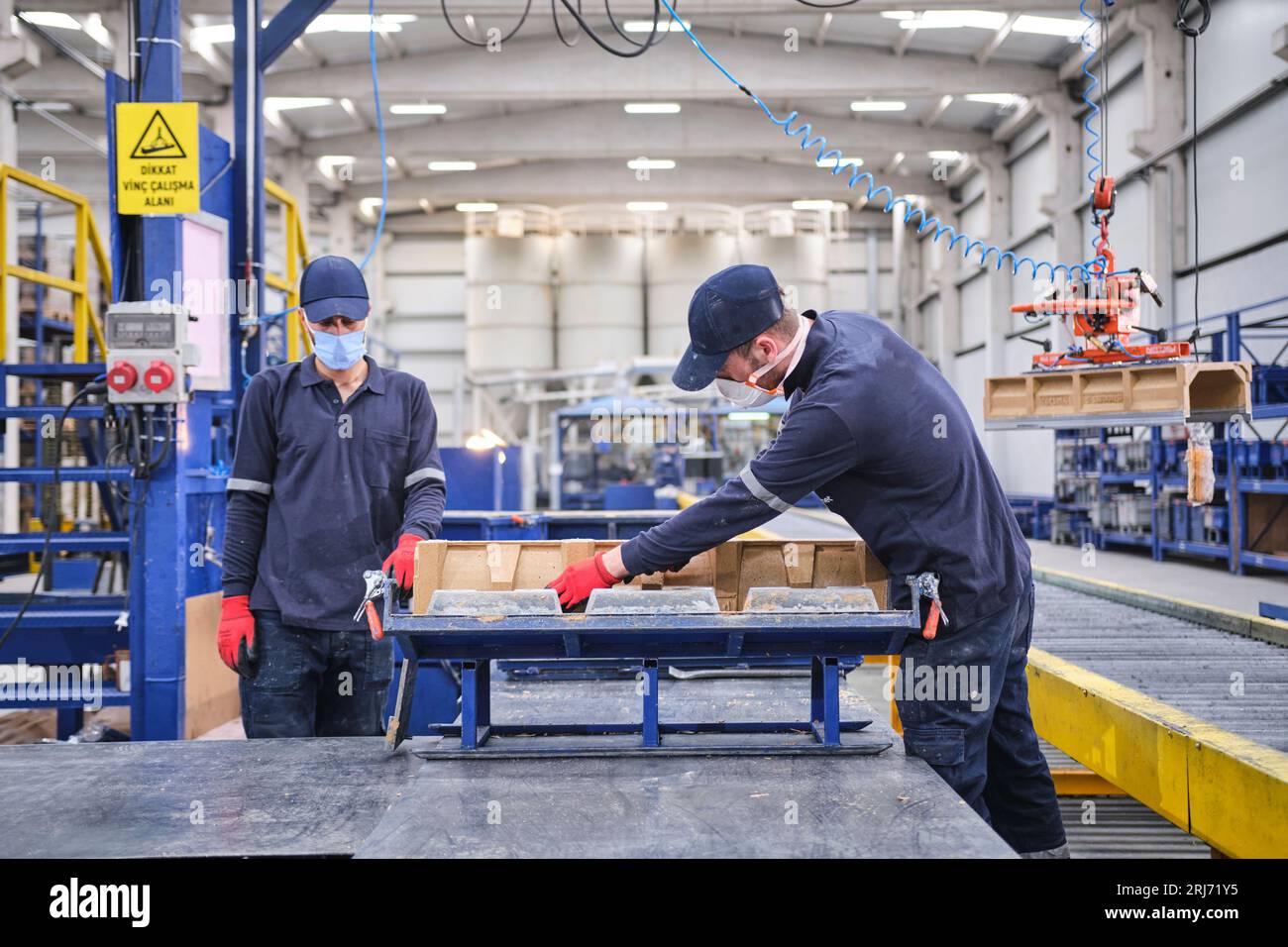 Werkarbeiter schüttet Zementmischung in eine Form und glättet sie mit einem Werkzeug. Stockfoto
