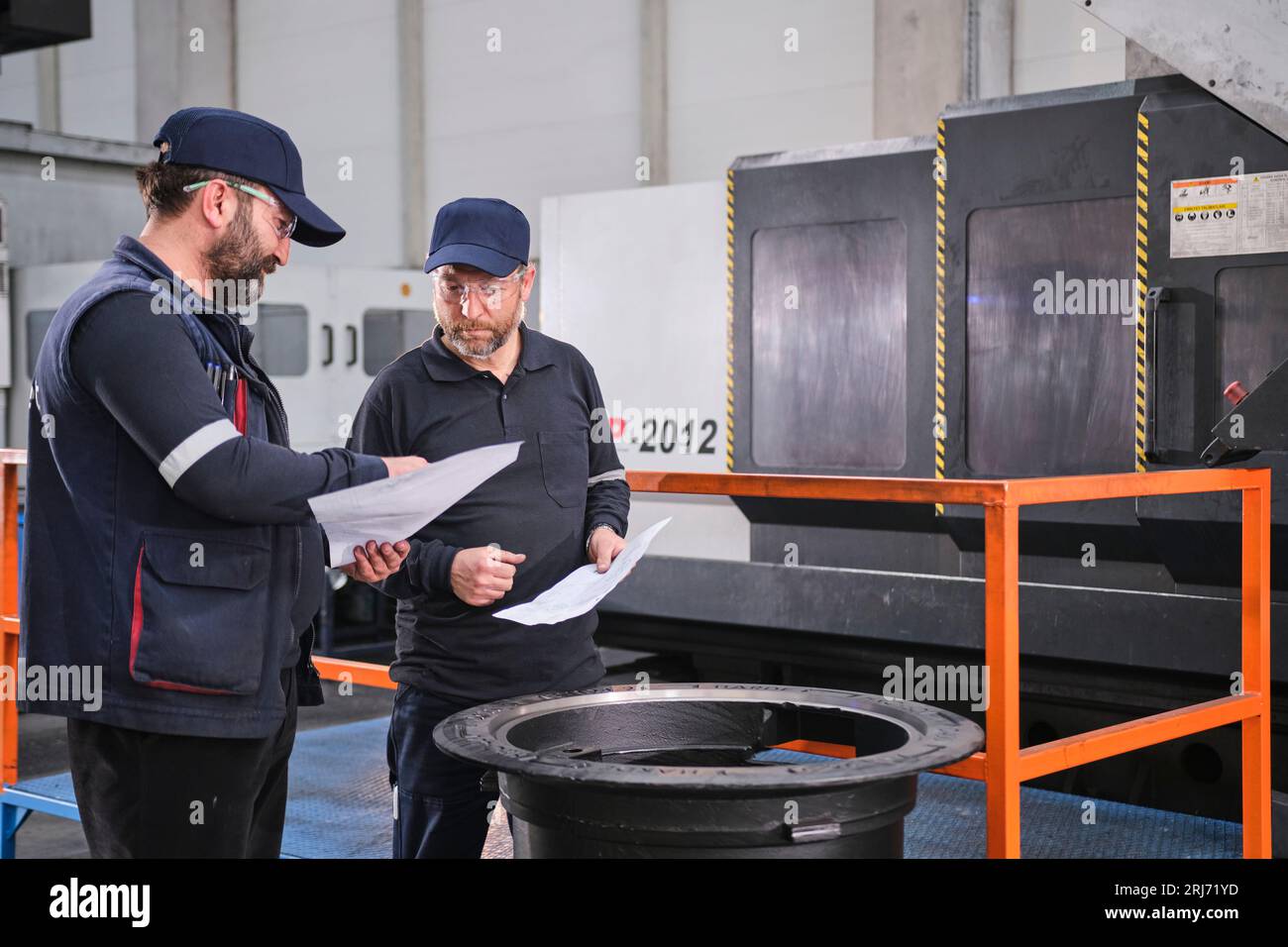 Werkarbeiter schüttet Zementmischung in eine Form und glättet sie mit einem Werkzeug. Stockfoto