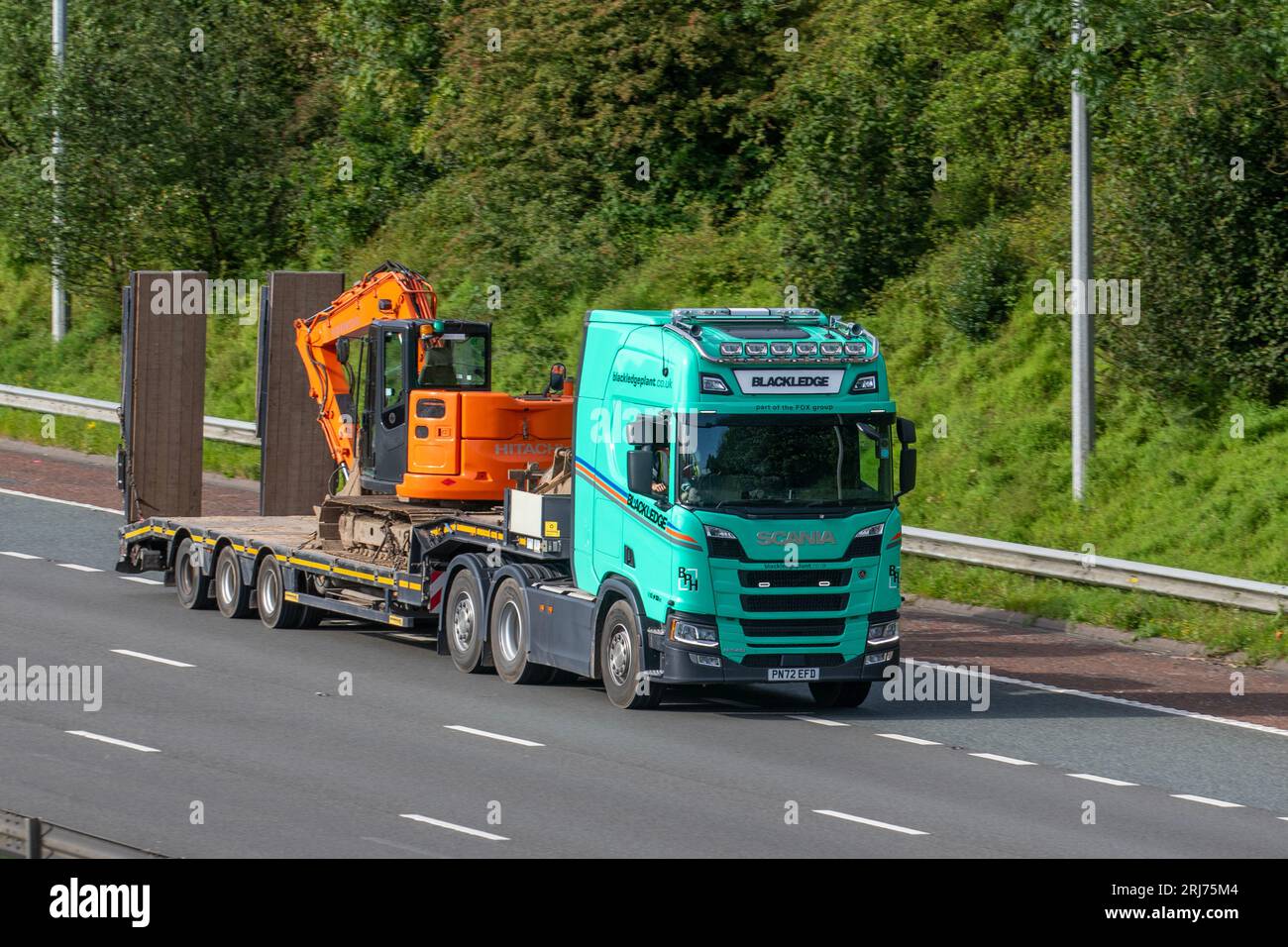 IN BLACKLEDGE WIRD EIN Scania R540 LKW mit Hitachi Raupenbagger auf Tieflader GEMIETET; Fahrt auf der Autobahn M6 im Großraum Manchester, Großbritannien Stockfoto