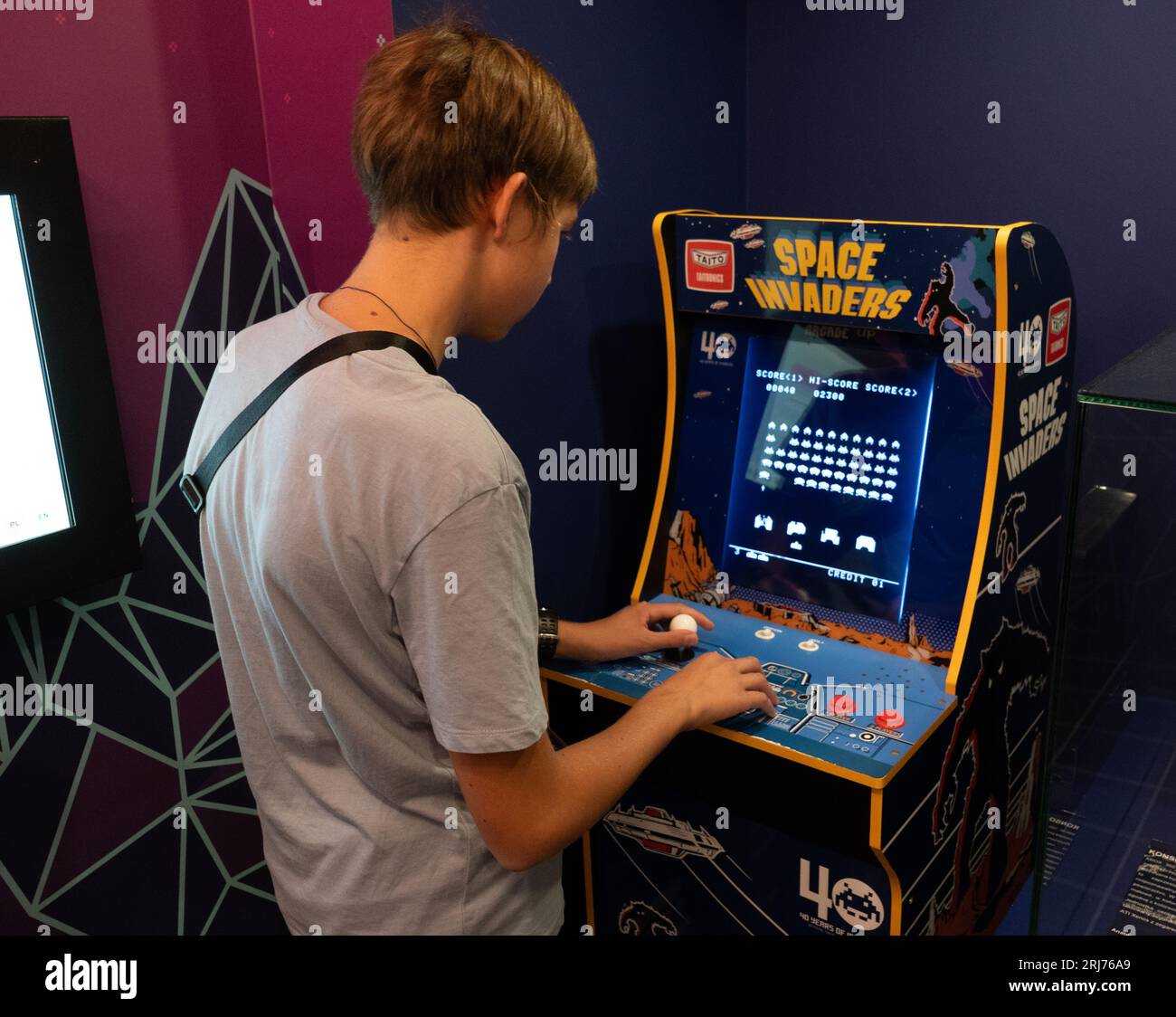 Raumeindringlinge Taito Spielmaschine. Simple Space Arcade in einem alten 8-Bit-Retro-Video. Boy spielt den klassischen Spielautomaten. Warschau, Polen - 28. Juli 2023. Stockfoto